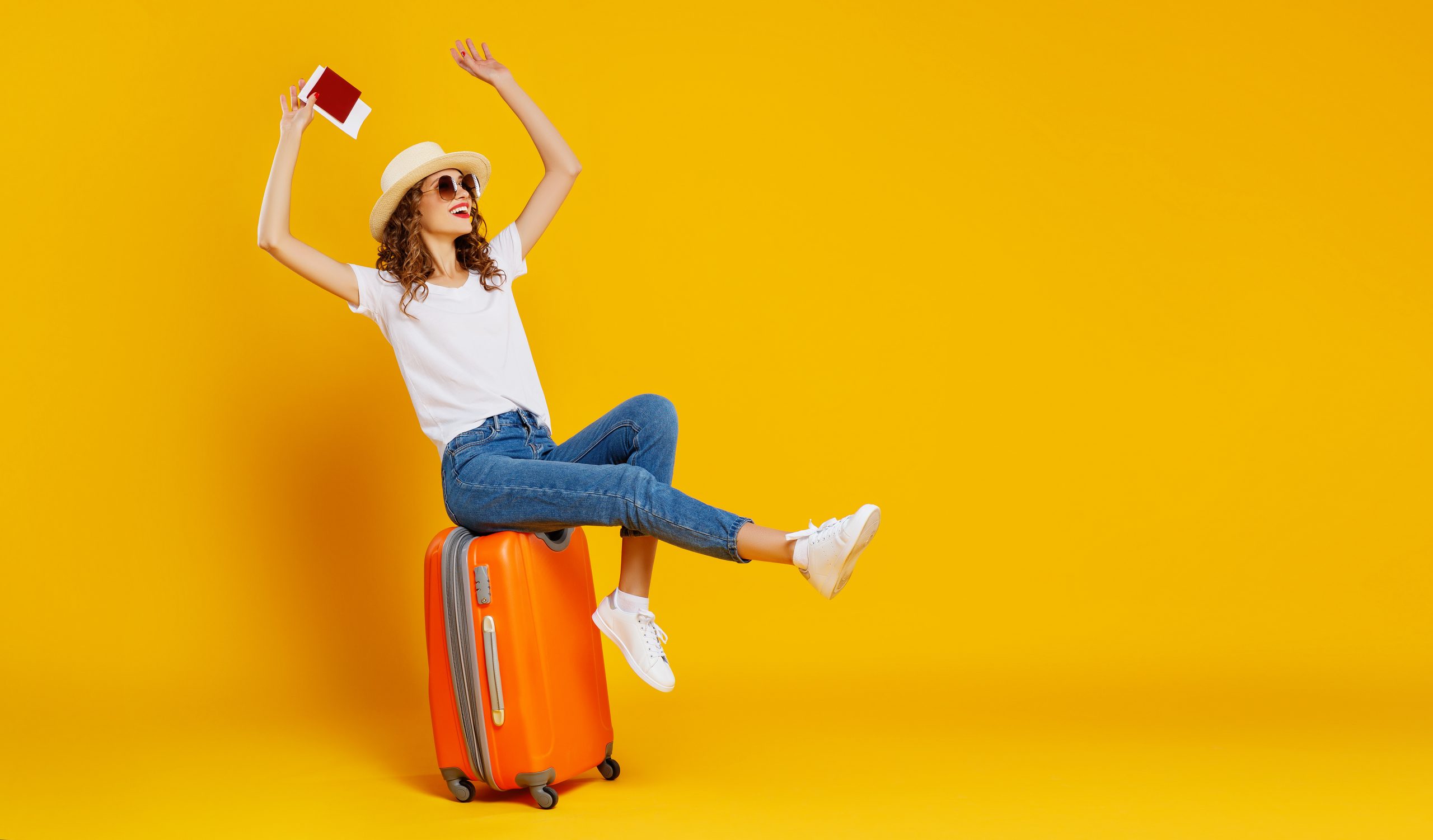 concept of travel. happy woman girl with suitcase and passport on yellow background